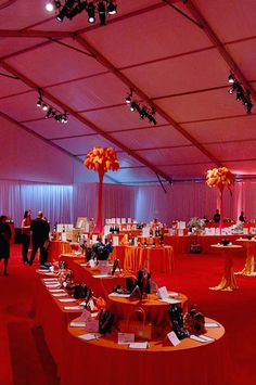 a red carpeted room with tables covered in orange cloths