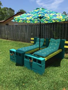 an umbrella and some blue couches in the grass