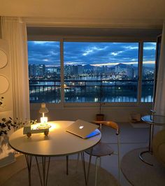 a living room with a table and chairs in front of a large window overlooking the city