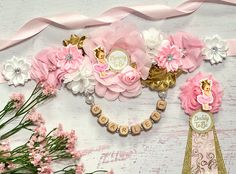 pink and white flowers are arranged on a wooden background with the name baby girl spelled out