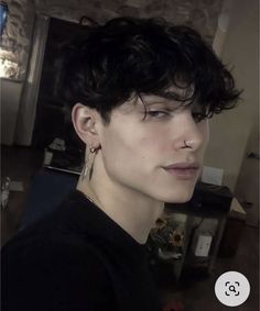 a young man with black hair and piercings on his ears looking at the camera