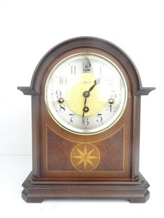 an old clock is sitting on a white surface