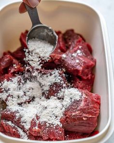 someone is scooping out some meat into a casserole dish with parmesan sprinkles