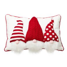 three knitted christmas hats sitting on top of a white pillow with red and white pom - poms