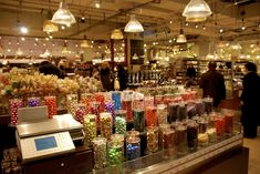 a store filled with lots of different colored candies and candy in front of a cash register