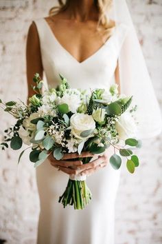 a bride holding a bouquet with greenery and an orange arrow on it's center