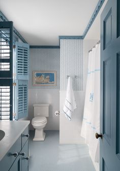 a blue and white bathroom with shutters open