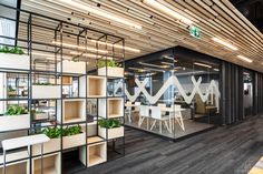 the interior of an office with plants growing on shelving units and tables in front of them