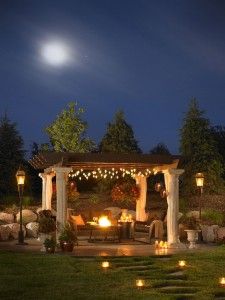 a gazebo lit up with candles in the night time for an outdoor seating area