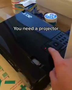 a hand is touching the back of a black laptop that's being used as a projector