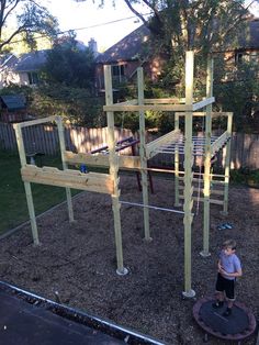 a young boy standing in front of a playground structure