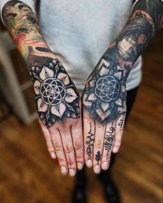 a person with tattoos on their hands and both holding the same object in one hand