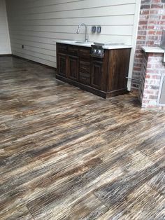 a kitchen with wood flooring next to a brick oven and stove top in an empty room