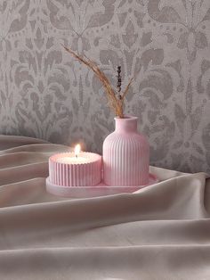 a pink vase with a lit candle on it