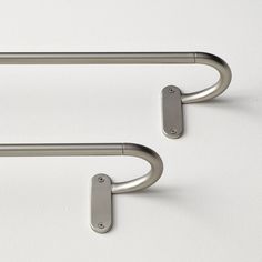 two stainless steel handles on a white surface with no one in the photo looking at them