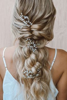 a woman with long blonde hair in a half - up braid and some leaves on her head