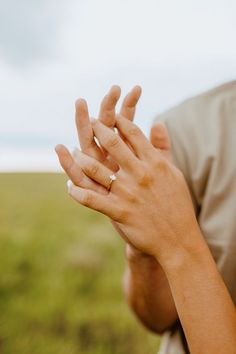 a woman is holding her hands together in the middle of an open field with grass