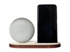 an electronic device and a ball on a wooden stand with a cell phone in the background