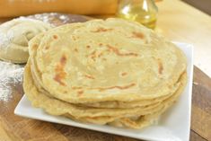 several flat breads on a white plate with powdered sugar and olive oil in the background