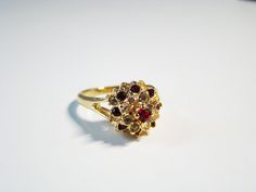 Gorgeous Garnet Ring-  gemstone- with dazzling crystals.  It shines like real gold. GREAT Gift! No Tarnish Size 6 1/4 Hallmarked ESPO - Joseph Esposito Gemstones: #1 - Garnet color CZ's, square diamond shape 3 X 3mm, faceted  #2 - White CZ's, round 1.2mm, faceted  It will come in a gift bag. Cubic Zirconia Cluster Ring With Sparkling Stones As Gift, Gold Multi-stone Flower Ring For Wedding, Gold Cluster Ruby Promise Ring, Gold Cluster Ruby Ring For Promise, Gold Cluster Birthstone Ring With Gemstone, Gold Cluster Multi-stone Diamond Ring, Gold Cluster Ruby Ring Fine Jewelry, Gold Multi-stone Crystal Promise Ring, Gold Multi-stone Cluster Ring For Anniversary