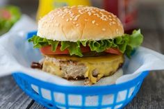 a cheeseburger with lettuce and tomato in a blue basket on a wooden table