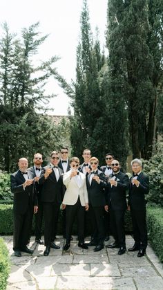 a group of men in tuxedos posing for a photo with their thumbs up