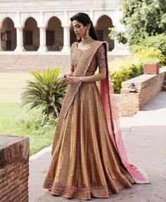 a woman in a gold and pink lehenga