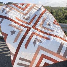 a large white and orange quilt sitting on the side of a road