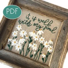 a cross stitch picture frame with daisies and the words it is well with my soul