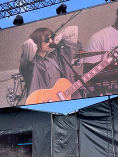 a man holding a guitar on top of a large screen