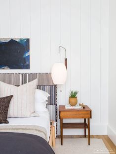 a bed sitting next to a night stand on top of a wooden table in a bedroom