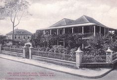 an old black and white photo of a house on the corner with a fence around it