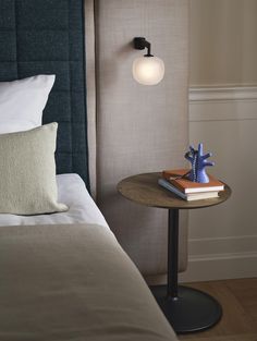 a small table with a book on it in front of a bed and headboard