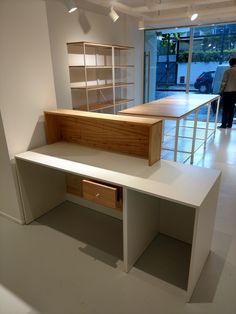 a white desk and shelves in a room with a man looking out the window behind it