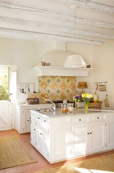 a kitchen with white cabinets and an island that has flowers on it in the center