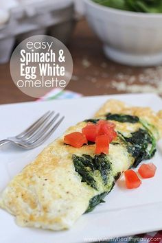 an omelette with spinach and red peppers on it sitting on a white plate