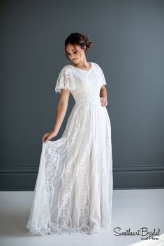 a woman in a white dress is posing for the camera with her hands on her hips