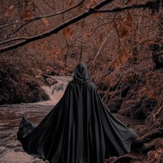 a person wearing a black cloak standing in the water