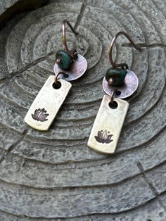 These unique dangle earrings are hand crafted from recycled brass and copper. The brass components are hand stamped with lotus flowers and the copper elements are accented with polished turquoise jasper stones.  The ear wires are 18g copper. If you require a different gauge or metal ear wire please let me know.  Length approx 3cm  width approx 13mm  READY TO SHIP!  Your earrings will arrive attractively packaged and ready for gifting or keeps.  please read shop policies before ordering Bohemian Stamped Copper Jewelry, Bronze Copper Spiritual Earrings, Spiritual Bronze Copper Earrings, Unique Dangle Earrings, Unique Jewelry Gifts, Jasper Stone, Mixed Metals, Lotus Flower, Flower Earrings