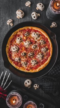 an overhead view of a pizza with skulls on it and candles in front of it