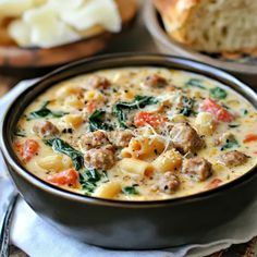 a bowl of soup with meat, cheese and spinach in it on a table