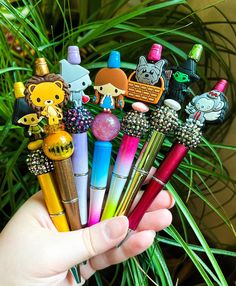 a person holding several pens in their hand with cartoon characters on them and other items sticking out of the pen