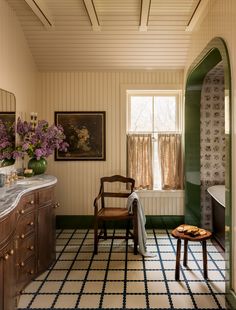 a chair and table in a room with flowers on the window sill next to it