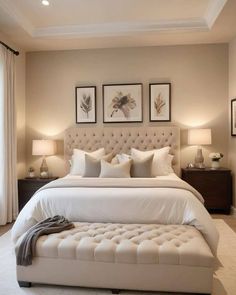 a large white bed sitting in a bedroom next to two lamps and pictures on the wall