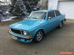 an old blue car is parked in front of a house with snow on the ground