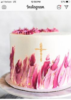 a white cake with pink flowers and a gold cross on top is sitting on a plate