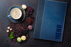 a book and some chocolates on a table with a cup of coffee next to it