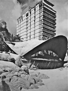 a black and white photo of a building in the background with snow on the ground