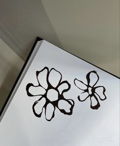 two black and white flowers are drawn on a piece of paper