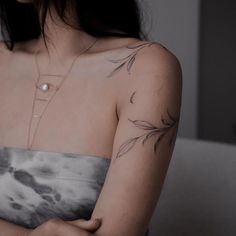 a woman with a tattoo on her arm and chest is looking down at the ground